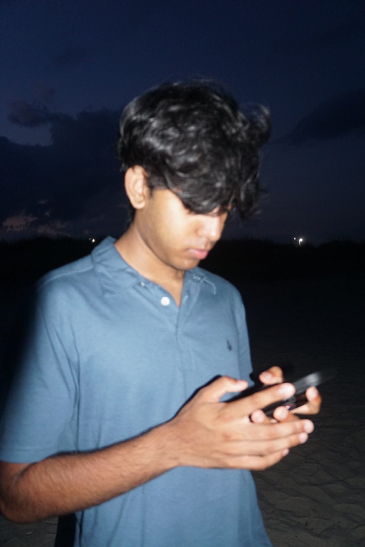 Shwetanshu checking his phone on a beach at dusk